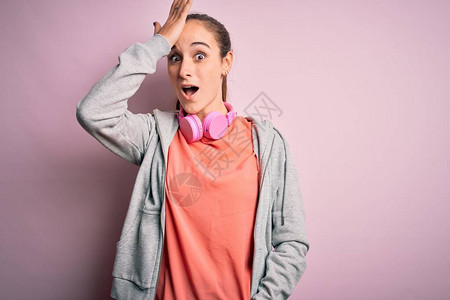 漂亮的运动型女人在粉红色的背景上用耳机听音乐图片