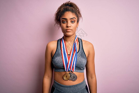 年轻非洲裔美国运动家女孩在孤立的粉红背景上打着体育奖牌图片