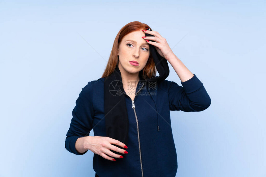 年轻红发女运动女青年身穿孤立蓝背景的蓝图片