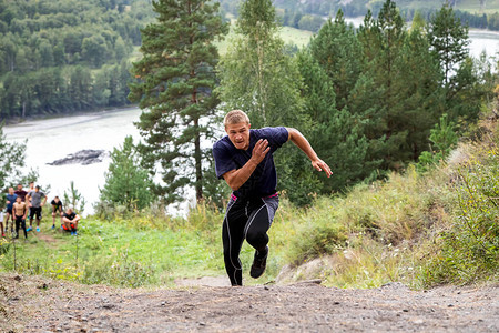 运动员运动员在背景山区河流山脉和森林中上坡短跑比赛快速移动和运图片