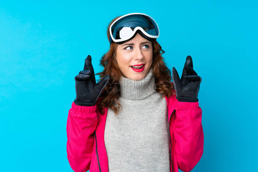 穿着滑雪眼镜的滑雪妇女在隔绝的蓝墙上图片