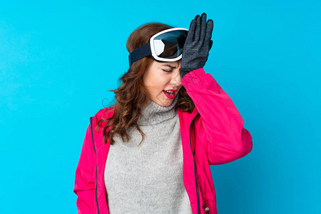 在孤立的蓝墙上戴滑雪板眼镜的滑雪女子图片