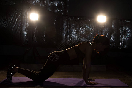 亚洲苗条健身女锻炼伸展腿手臂在雾烟黑暗背景低曝光环境中锻炼肌肉手臂图片