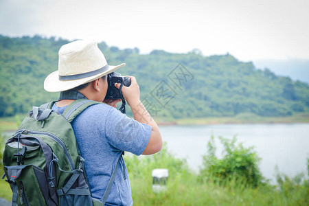 一个戴着帽子的小亚裔男孩喜欢去自然世界旅行拿着相机拍图片