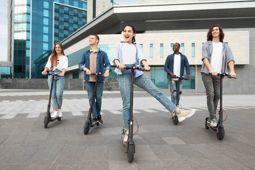 5名兴奋的散校学生在城里骑着摩托式脚踏图片