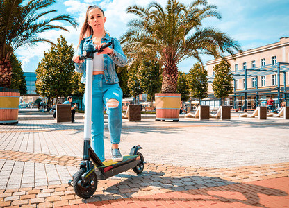 滑板车女孩使用从女商人那里踢电动城市自行车现代图片
