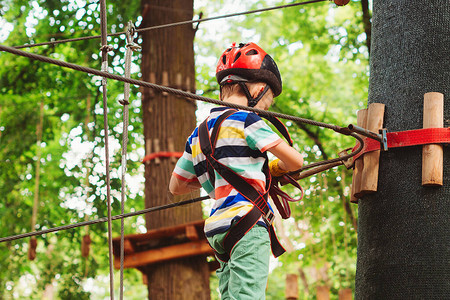可爱的男孩在冒险绳索公园孩子从事攀岩孩子通过绳索路上的障碍物夏令营健康的运动童年背景图片