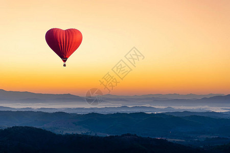 心形红色热气球飞越山峦图片
