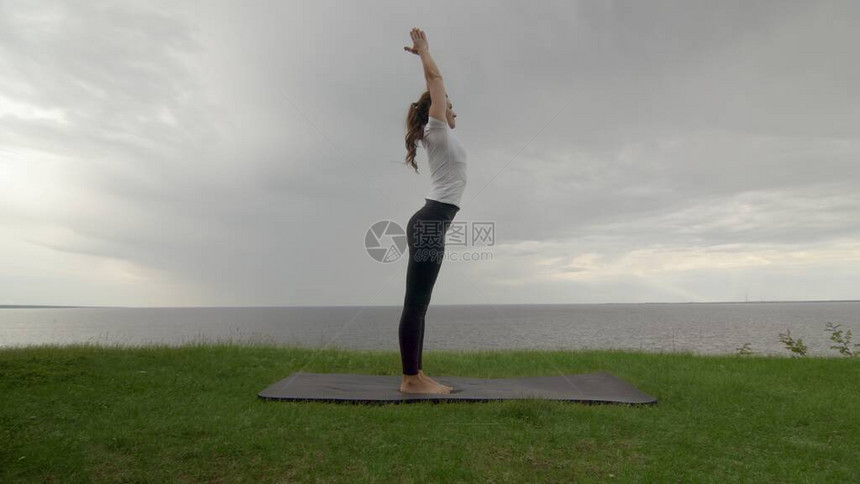 在湖边或海边的海岸上做瑜伽的年轻适龄女子女在山上图片