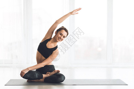 快乐的女士在莲花姿势和伸展臂下锻炼图片