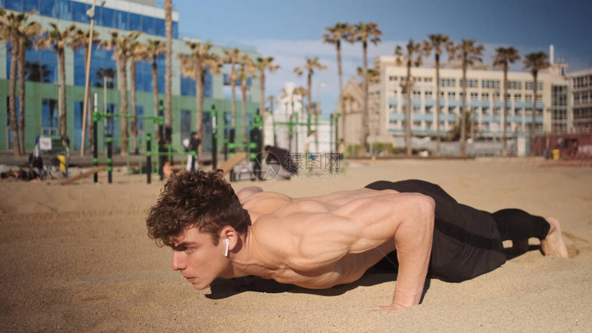年轻有吸引力的肌肉男在海滩上进行功能训练时推车图片