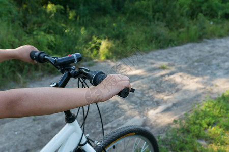 男孩在绿色森林的乡村道路上骑自行车时图片