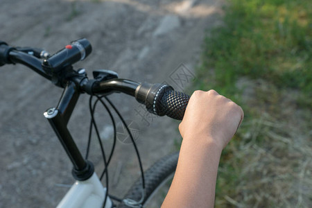男孩在农村路上骑自行车时手握着黑色的脚踏车把手图片