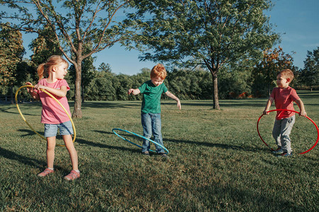 可爱的微笑高加索学龄前女孩男朋友在外面的公园里玩呼啦圈儿童体育活动生活方式快乐的童年孩子们的夏季节背景
