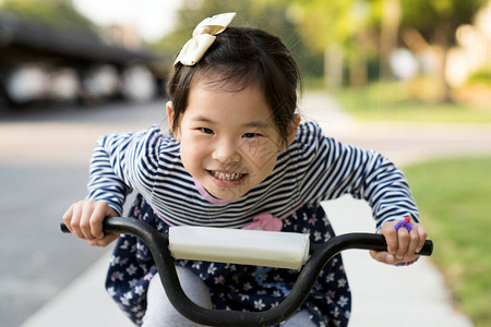 可爱的亚洲小女孩不戴头盔就学骑自行车图片