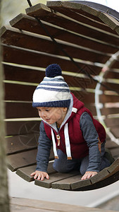 勇敢的小男孩爬上木隧道在冒图片