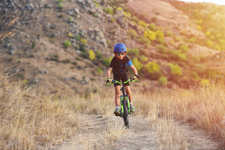 快乐的7岁男孩在秋天的公园里骑着自行车在美丽的秋天玩耍戴自行车头图片