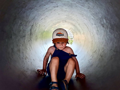 一个两岁小孩在西班牙巴塞罗那一个户外冒险公园的金属隧道里玩耍长得一图片