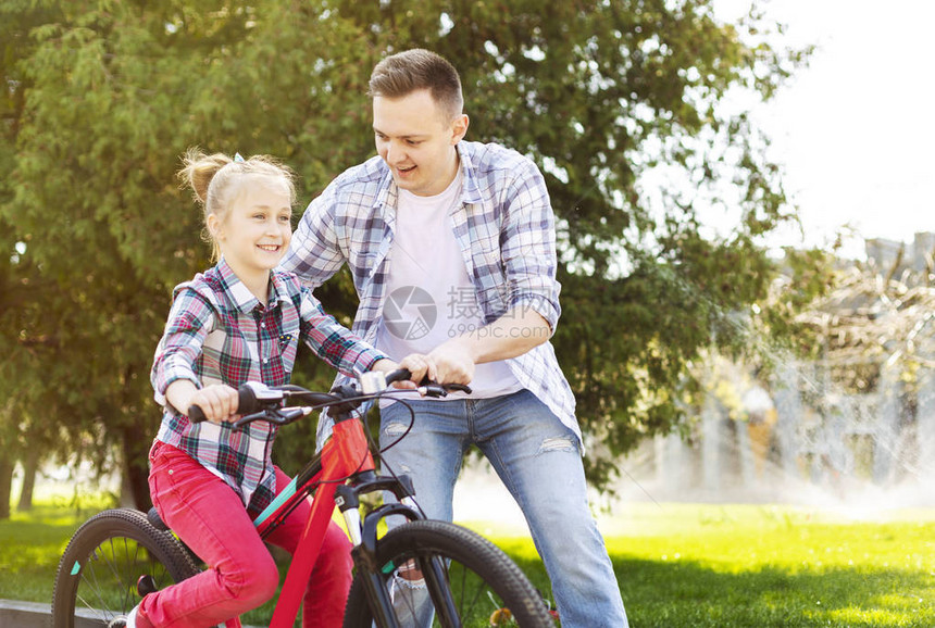 父亲在教他女儿骑自行车图片
