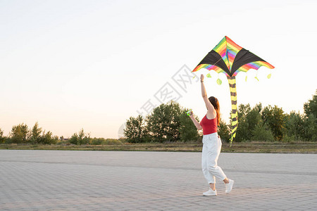 活跃的生活方式幸福的概念快乐的年轻女子在日落时带着风筝在公图片