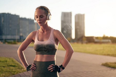 穿着运动服和耳机的肌肉发达的女人在锻炼和听音乐后休息图片
