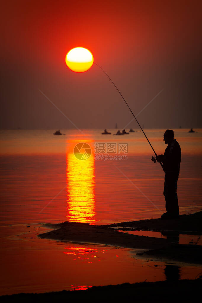 日落时旋转的钓鱼渔夫的剪影图片