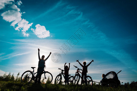 快乐的母亲和孩子在日落时骑自行车图片