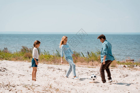 父母与女儿在海滩玩足球的选择关注焦图片