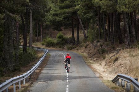 穿着红色和黑色衣服的男骑自行车男子骑车者在山坡后视线图片