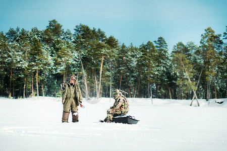 冬天季捕冬钓鱼两个渔民在森林背景下背景图片