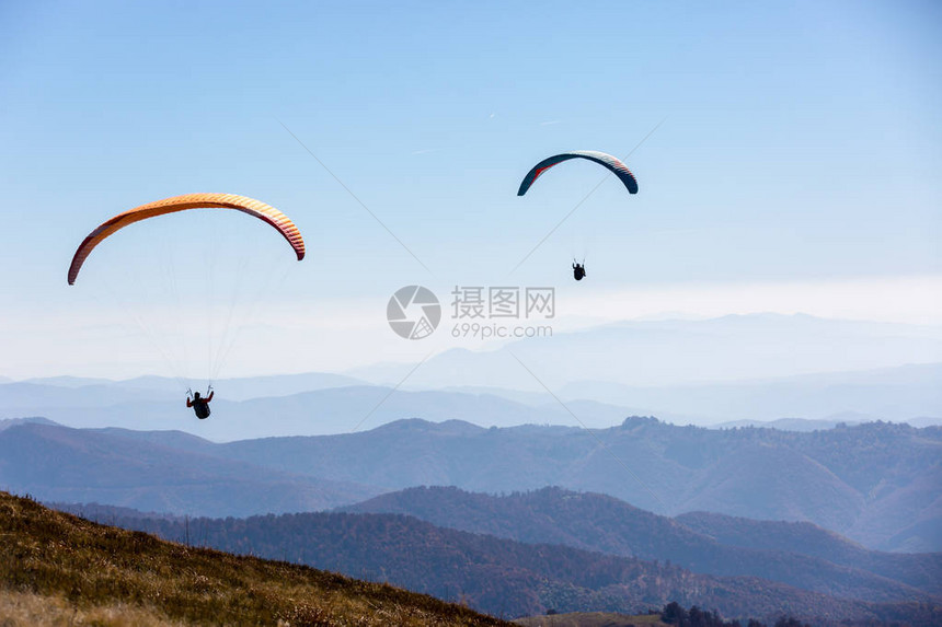 两架滑翔伞在山上飞翔图片