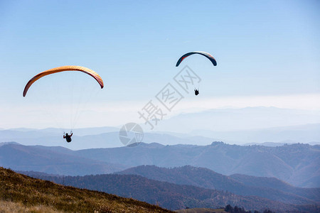 两架滑翔伞在山上飞翔图片