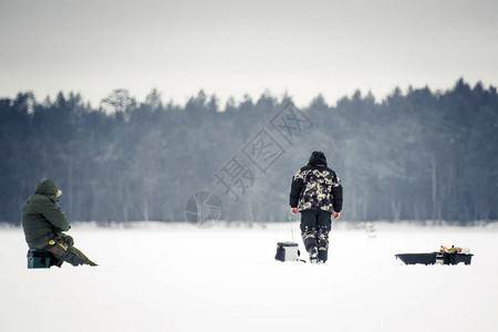 赫哲族冬捕冬天季捕冬钓鱼两个渔民在森林背景下背景