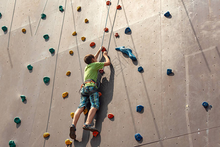 这男孩爬到一个极端公园的人造墙顶上握图片
