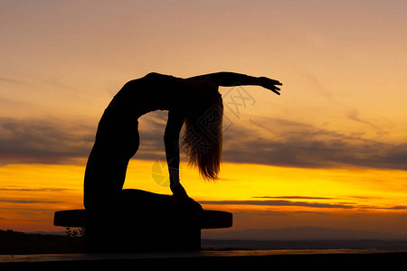 剪影女人教练瑜伽练习在日落瑜伽概念骆驼式Ustrasa图片