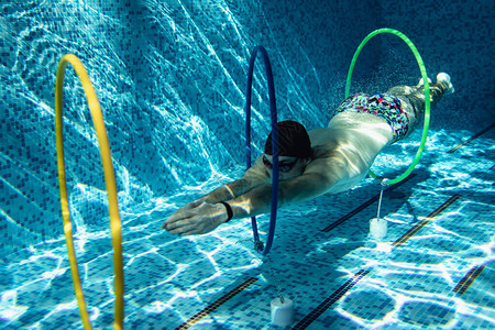 穿帽子和游泳护目镜的男教练在水下用图片