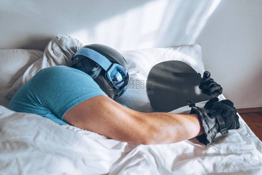 男人在床上与滑雪谷歌和头盔图片