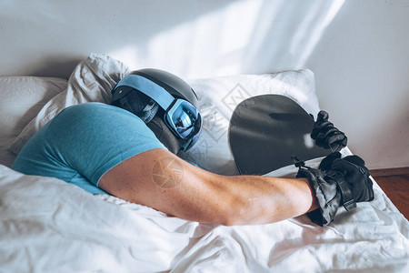 男人在床上与滑雪谷歌和头盔图片