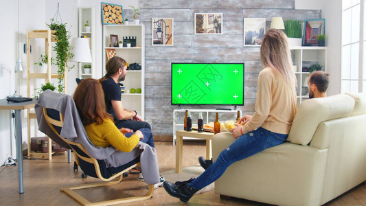 在客厅看足球比赛时亲近朋友的后视线在图片