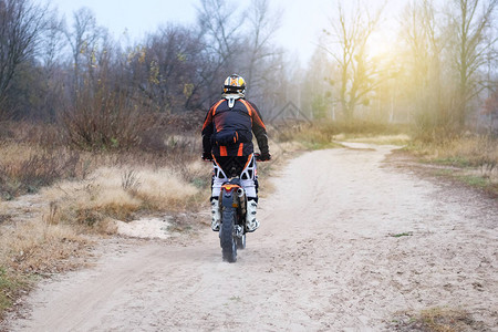 运动和积极的健康生活概念摩托车手在保护后秋天森林中骑着摩托车坐在阳光图片