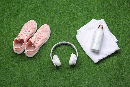 彩色背景上的运动鞋毛巾水瓶和耳机图片