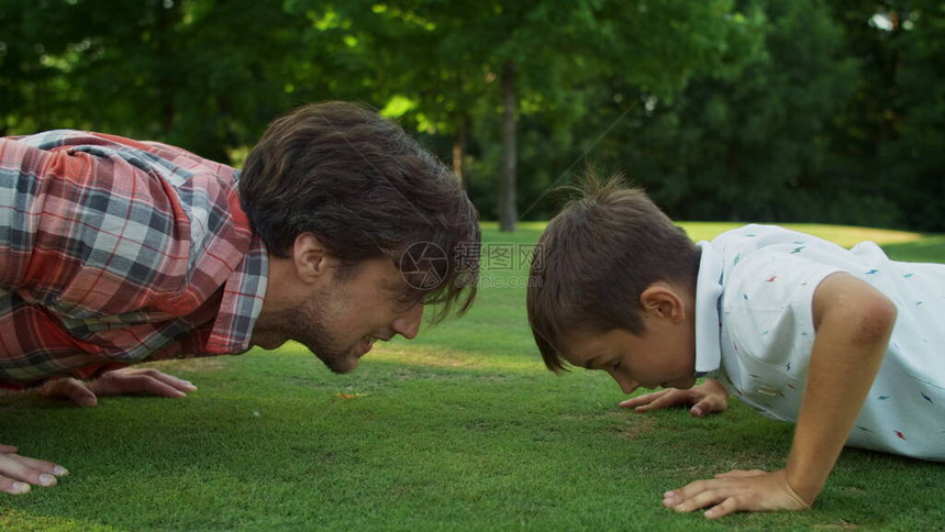 特写英俊的男人和男孩在草地上做俯卧撑快乐的父子在夏日公园一起训练幸福的家庭在户外锻炼男父母和儿子图片