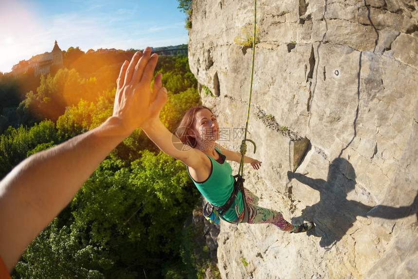 女孩爬上岩石一个女人在大自然中从事健身攀登者在克服攀登路线后给予五个同伴实现目标的喜悦团队图片