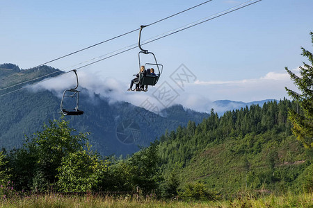 游客们享受喀尔巴阡山脉运输系统椅子升降机上的山地景图片