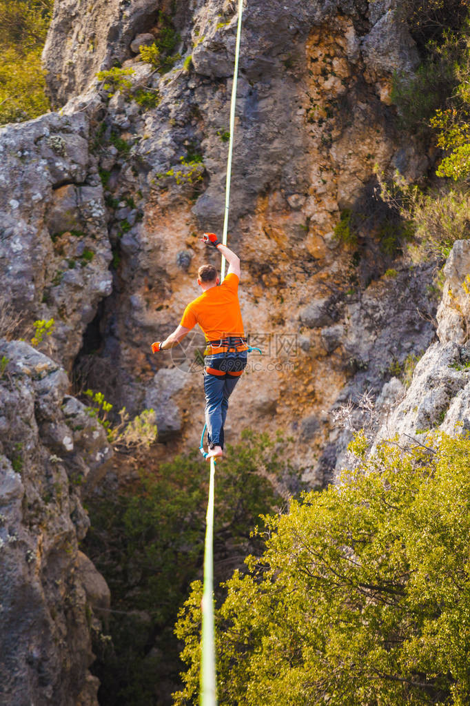 一个人正沿着一条拉长的吊索行走山中的高线人抓住平衡走钢丝者在大自然中的表现Highliner图片