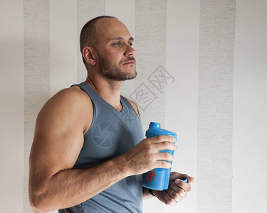 一个男人拿着一瓶蛋白质奶昔的画像运动员体育概念配置文件中的图片