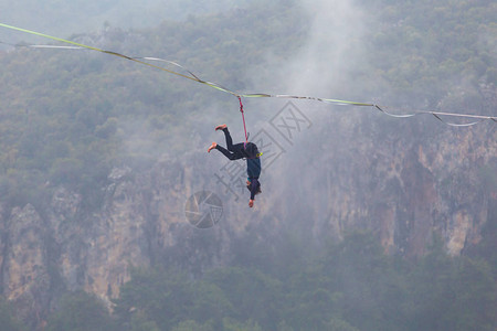 女孩跌倒在拉伸的吊索上山中的高线女人失去了平衡走钢丝者在大自然中的表现Highliner挂在绳子上图片
