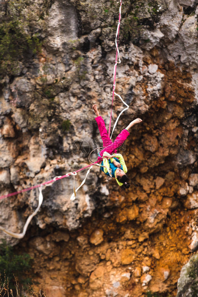 女孩落在一个拉伸的吊索上山中的高线女人失去了平衡自然界中的演讲走钢丝者Highliner挂在绳子上图片