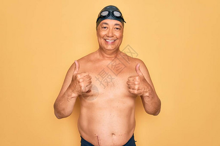 中年白发游泳男子穿着泳衣帽子和护目镜成功标志用手做积极的手势图片