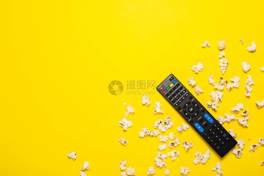 黄色背景上的电视遥控器电视调谐器或音频系统和爆米花概念系列电影体育横幅图片